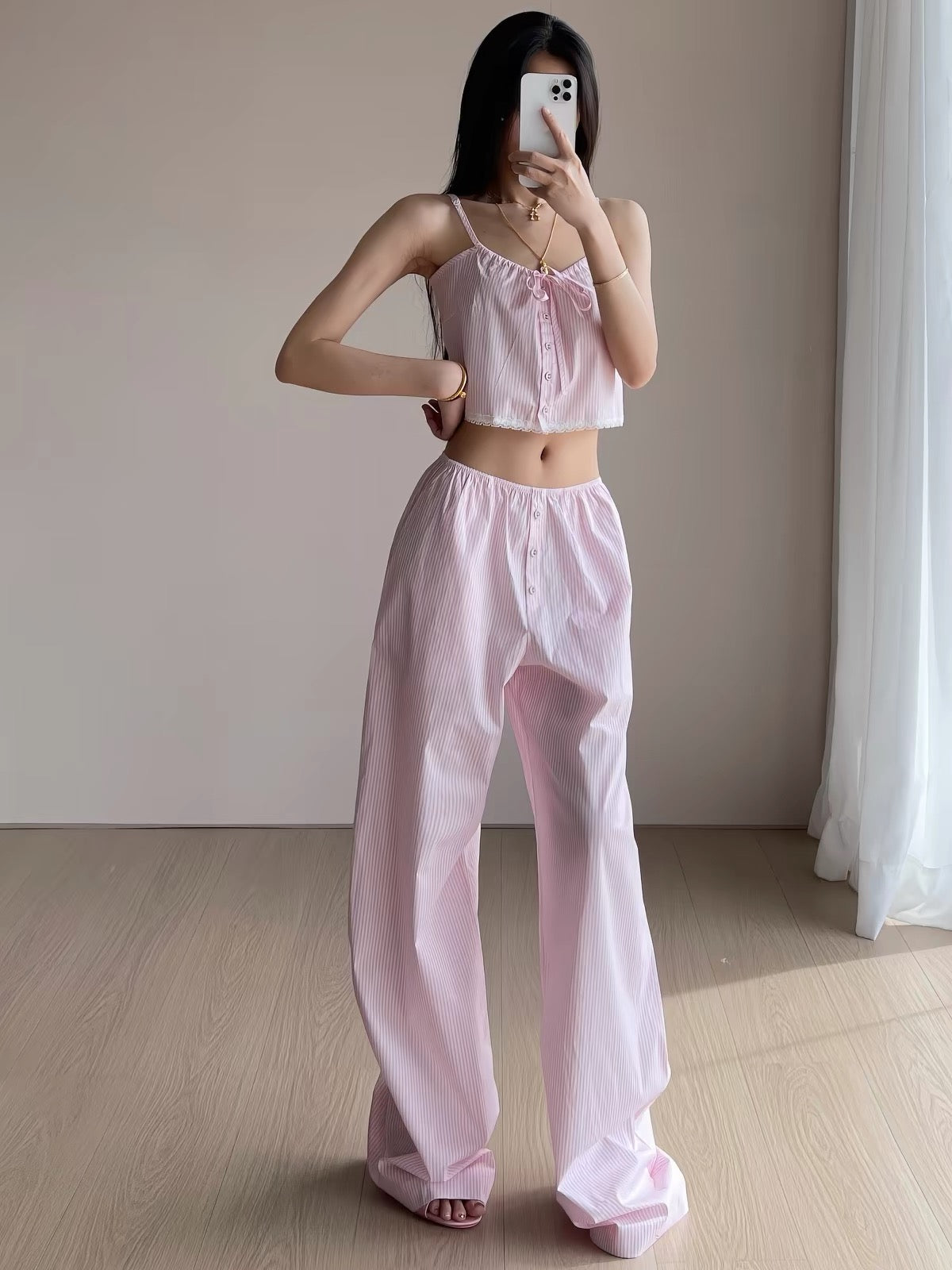 Woman wearing pink striped cropped cami with bow and lace hem and matching wide-leg pajama pants