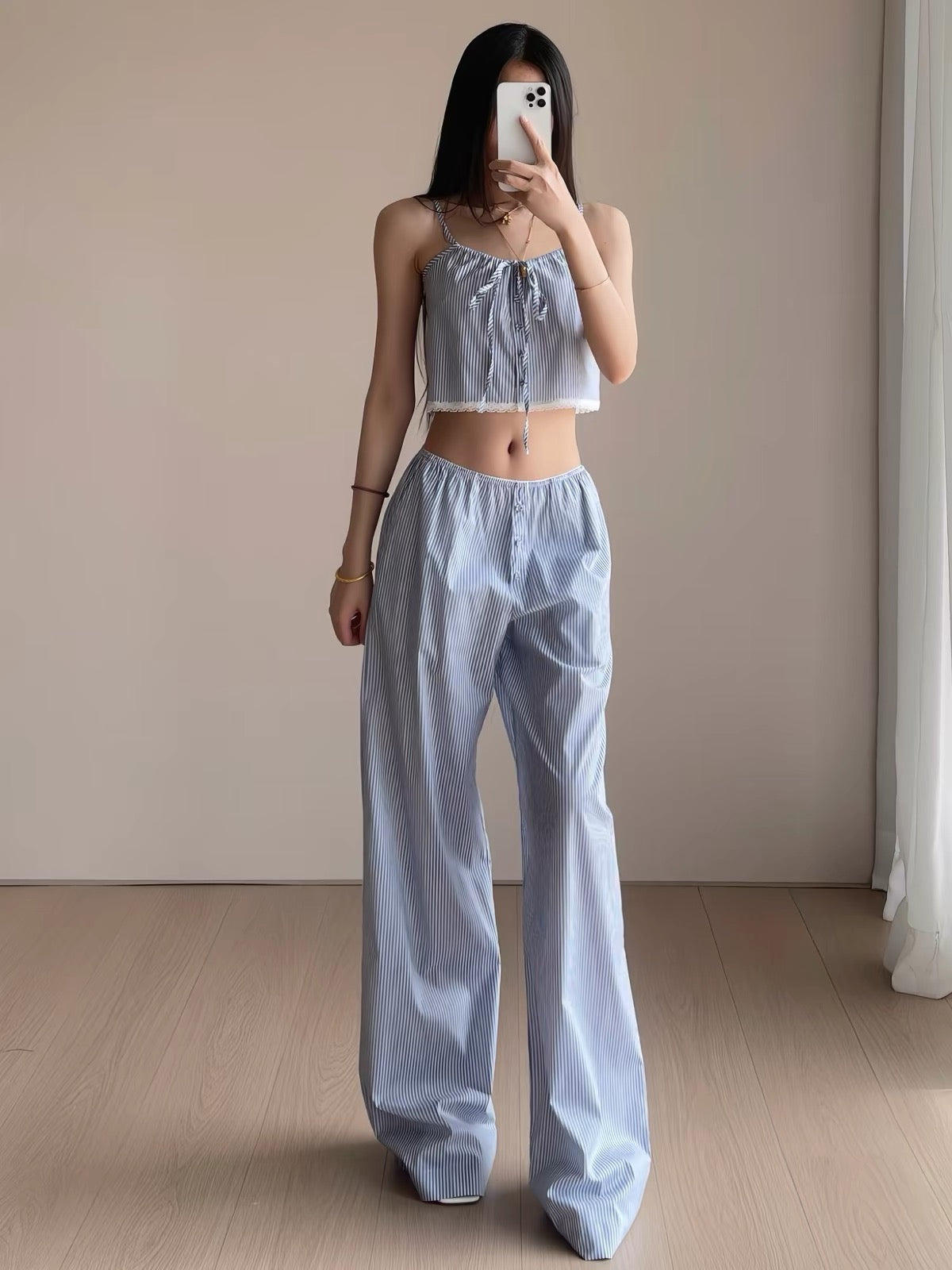 Woman wearing blue striped cropped cami with bow and lace hem and matching wide-leg pajama pants